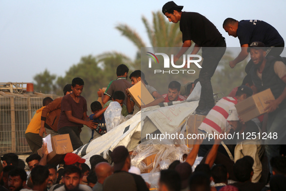 Palestinians are climbing onto trucks to grab aid that is being delivered into Gaza through a U.S.-built pier, amid the ongoing conflict bet...