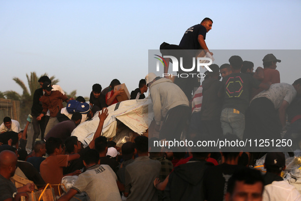 Palestinians are climbing onto trucks to grab aid that is being delivered into Gaza through a U.S.-built pier, amid the ongoing conflict bet...