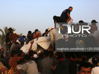 Palestinians are climbing onto trucks to grab aid that is being delivered into Gaza through a U.S.-built pier, amid the ongoing conflict bet...