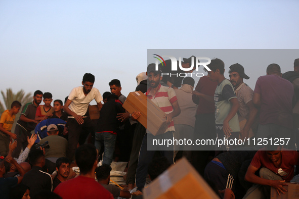 Palestinians are climbing onto trucks to grab aid that is being delivered into Gaza through a U.S.-built pier, amid the ongoing conflict bet...