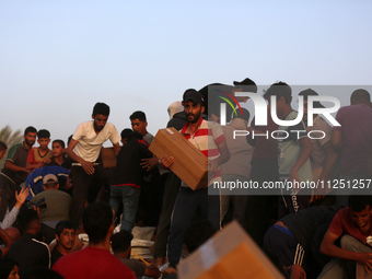 Palestinians are climbing onto trucks to grab aid that is being delivered into Gaza through a U.S.-built pier, amid the ongoing conflict bet...