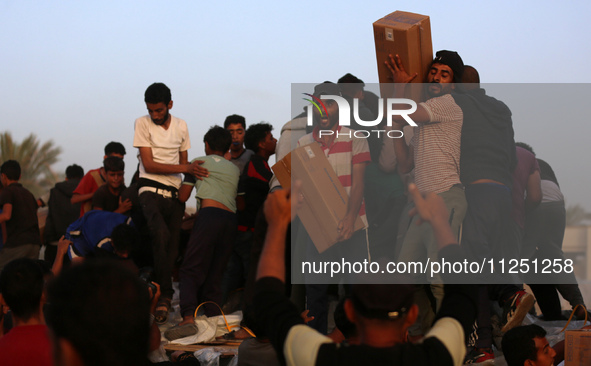 Palestinians are climbing onto trucks to grab aid that is being delivered into Gaza through a U.S.-built pier, amid the ongoing conflict bet...