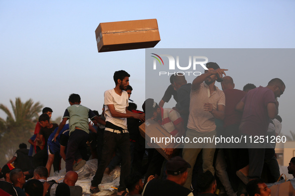 Palestinians are climbing onto trucks to grab aid that is being delivered into Gaza through a U.S.-built pier, amid the ongoing conflict bet...