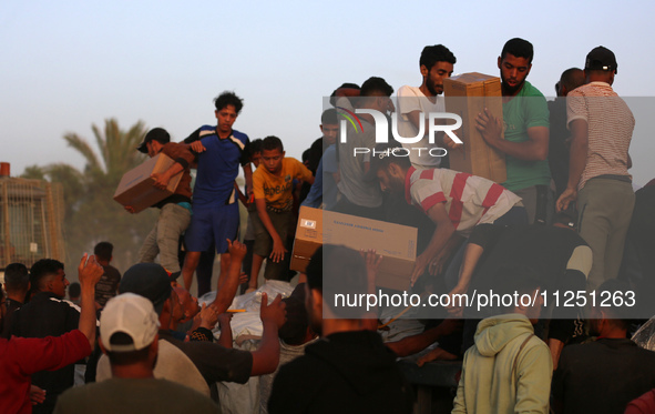 Palestinians are climbing onto trucks to grab aid that is being delivered into Gaza through a U.S.-built pier, amid the ongoing conflict bet...