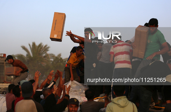 Palestinians are climbing onto trucks to grab aid that is being delivered into Gaza through a U.S.-built pier, amid the ongoing conflict bet...