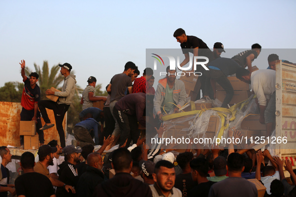 Palestinians are climbing onto trucks to grab aid that is being delivered into Gaza through a U.S.-built pier, amid the ongoing conflict bet...