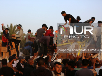 Palestinians are climbing onto trucks to grab aid that is being delivered into Gaza through a U.S.-built pier, amid the ongoing conflict bet...