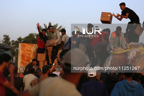 Palestinians are climbing onto trucks to grab aid that is being delivered into Gaza through a U.S.-built pier, amid the ongoing conflict bet...