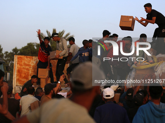 Palestinians are climbing onto trucks to grab aid that is being delivered into Gaza through a U.S.-built pier, amid the ongoing conflict bet...