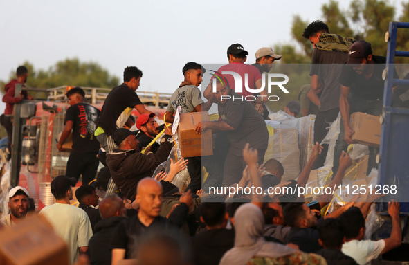 Palestinians are climbing onto trucks to grab aid that is being delivered into Gaza through a U.S.-built pier, amid the ongoing conflict bet...