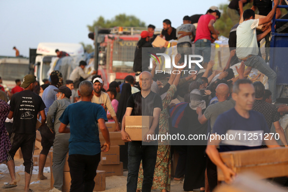 Palestinians are carrying boxes of aid that are being delivered into Gaza through a U.S.-built pier, amid the ongoing conflict between Israe...