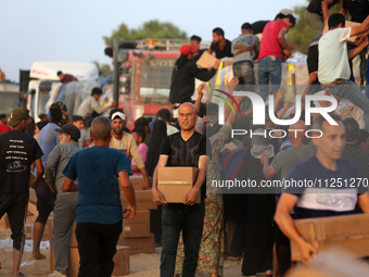 Palestinians are carrying boxes of aid that are being delivered into Gaza through a U.S.-built pier, amid the ongoing conflict between Israe...