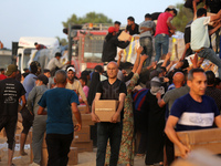 Palestinians are carrying boxes of aid that are being delivered into Gaza through a U.S.-built pier, amid the ongoing conflict between Israe...