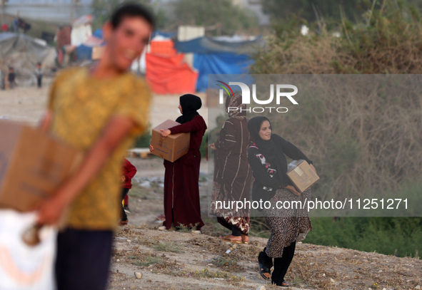 Palestinians are carrying boxes of aid that are being delivered into Gaza through a U.S.-built pier, amid the ongoing conflict between Israe...