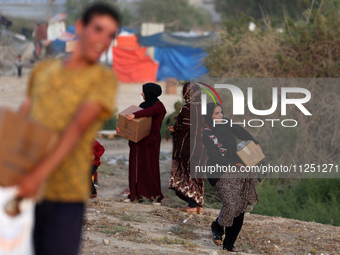 Palestinians are carrying boxes of aid that are being delivered into Gaza through a U.S.-built pier, amid the ongoing conflict between Israe...