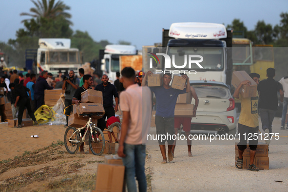 Palestinians are carrying boxes of aid that are being delivered into Gaza through a U.S.-built pier, amid the ongoing conflict between Israe...