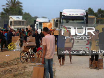 Palestinians are carrying boxes of aid that are being delivered into Gaza through a U.S.-built pier, amid the ongoing conflict between Israe...