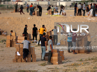 Palestinians are carrying boxes of aid that are being delivered into Gaza through a U.S.-built pier, amid the ongoing conflict between Israe...