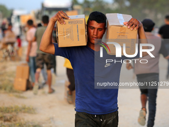 Palestinians are carrying boxes of aid that are being delivered into Gaza through a U.S.-built pier, amid the ongoing conflict between Israe...