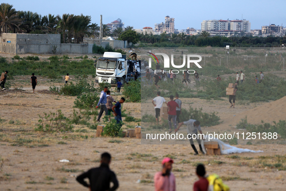 Palestinians are climbing onto trucks to grab aid that is being delivered into Gaza through a U.S.-built pier, amid the ongoing conflict bet...