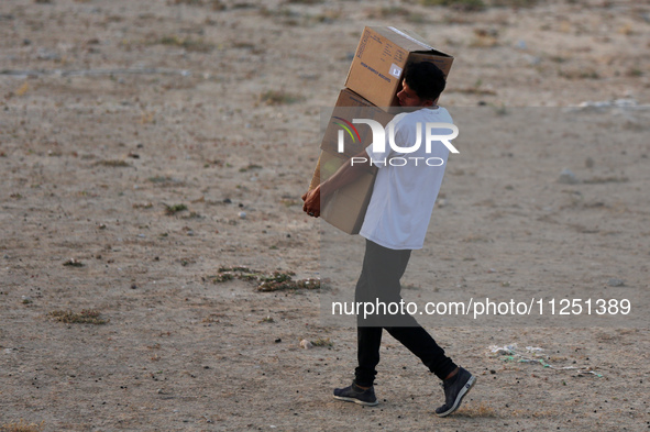 Palestinians are carrying boxes of aid that are being delivered into Gaza through a U.S.-built pier, amid the ongoing conflict between Israe...