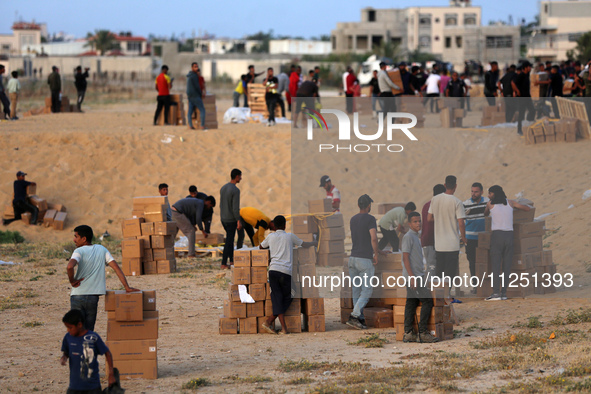 Palestinians are carrying boxes of aid that are being delivered into Gaza through a U.S.-built pier, amid the ongoing conflict between Israe...