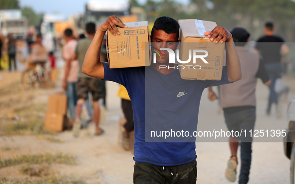 Palestinians are carrying boxes of aid that are being delivered into Gaza through a U.S.-built pier, amid the ongoing conflict between Israe...