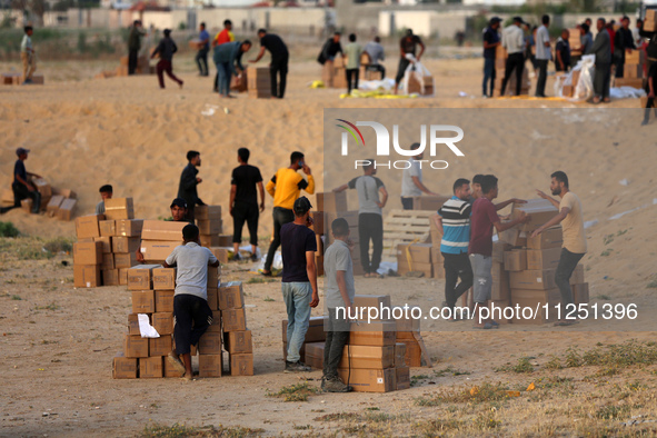 Palestinians are carrying boxes of aid that are being delivered into Gaza through a U.S.-built pier, amid the ongoing conflict between Israe...