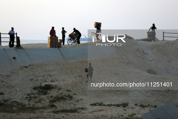 Palestinians are carrying boxes of aid that are being delivered into Gaza through a U.S.-built pier, amid the ongoing conflict between Israe...