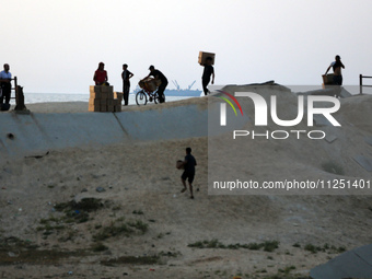 Palestinians are carrying boxes of aid that are being delivered into Gaza through a U.S.-built pier, amid the ongoing conflict between Israe...