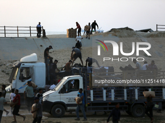 Palestinians are carrying boxes of aid that are being delivered into Gaza through a U.S.-built pier, amid the ongoing conflict between Israe...