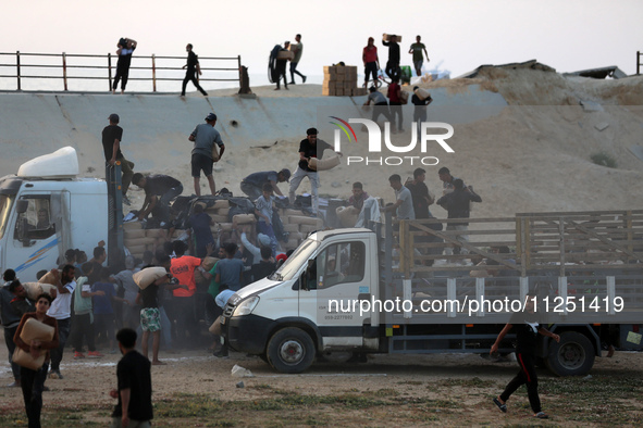 Palestinians are climbing onto trucks to grab aid that is being delivered into Gaza through a U.S.-built pier, amid the ongoing conflict bet...