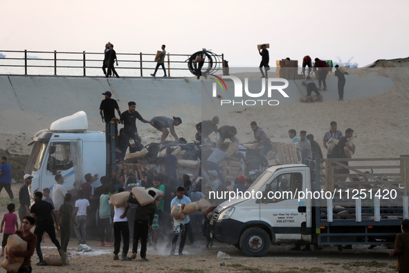 Palestinians are climbing onto trucks to grab aid that is being delivered into Gaza through a U.S.-built pier, amid the ongoing conflict bet...