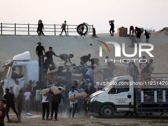 Palestinians are climbing onto trucks to grab aid that is being delivered into Gaza through a U.S.-built pier, amid the ongoing conflict bet...