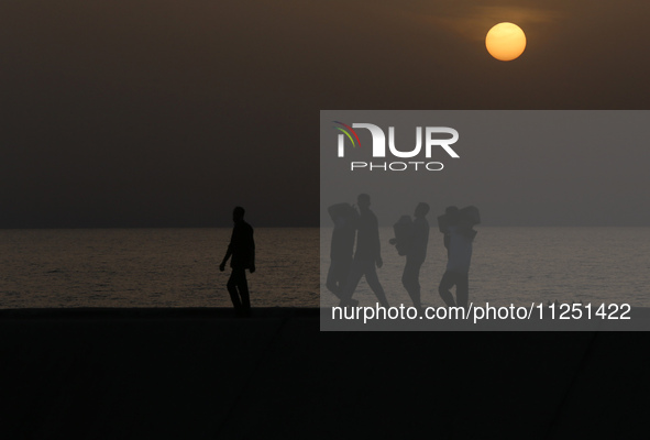 Palestinians are carrying boxes of aid that are being delivered into Gaza through a U.S.-built pier, amid the ongoing conflict between Israe...