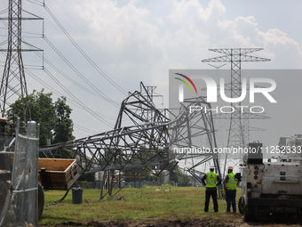 Electrical workers are looking toward a mangled transmission tower at the intersection of Gardendale Dr. and Antoine Dr. as crews throughout...