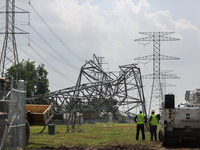 Electrical workers are looking toward a mangled transmission tower at the intersection of Gardendale Dr. and Antoine Dr. as crews throughout...