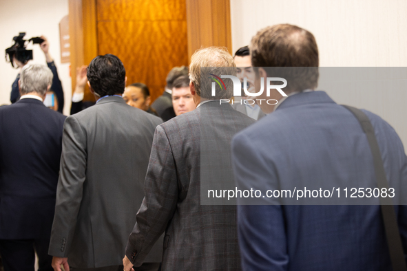 Texas Attorney General Ken Paxton is walking with his entourage toward the courtroom at the Harris County Criminal Justice Center in Houston...