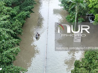 A citizen is riding in 50 cm of water after heavy rain in Nanning, China, on May 19, 2024. (