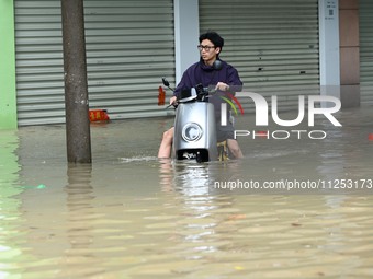 A citizen is riding in 50 cm of water after heavy rain in Nanning, China, on May 19, 2024. (