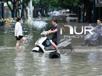 Citizens are riding in 50 cm of water after heavy rain in Nanning, China, on May 19, 2024. (