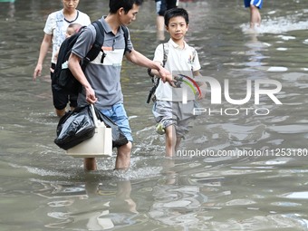 Citizens are walking on a flooded road after heavy rain in Nanning, China, on May 19, 2024. (