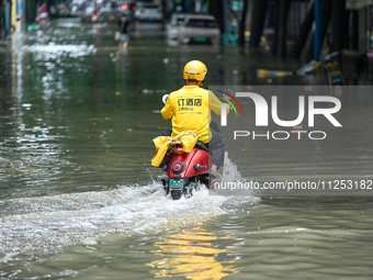 A courier is riding on a flooded road after heavy rain in Nanning, China, on May 19, 2024. (