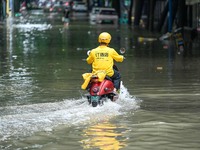 A courier is riding on a flooded road after heavy rain in Nanning, China, on May 19, 2024. (