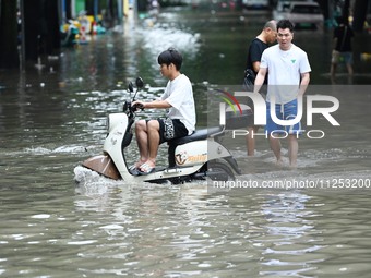 A citizen is riding in 50 cm of water after heavy rain in Nanning, China, on May 19, 2024. (