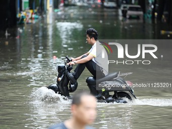 A citizen is riding in 50 cm of water after heavy rain in Nanning, China, on May 19, 2024. (