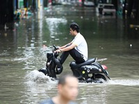 A citizen is riding in 50 cm of water after heavy rain in Nanning, China, on May 19, 2024. (