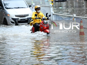 A citizen is riding in 50 cm of water after heavy rain in Nanning, China, on May 19, 2024. (