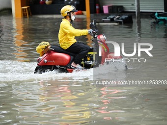 A citizen is riding in 50 cm of water after heavy rain in Nanning, China, on May 19, 2024. (