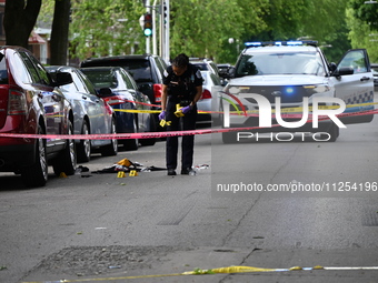 A crime scene investigator is placing evidence markers at the crime scene to show where a recovered firearm, articles of clothing, and other...